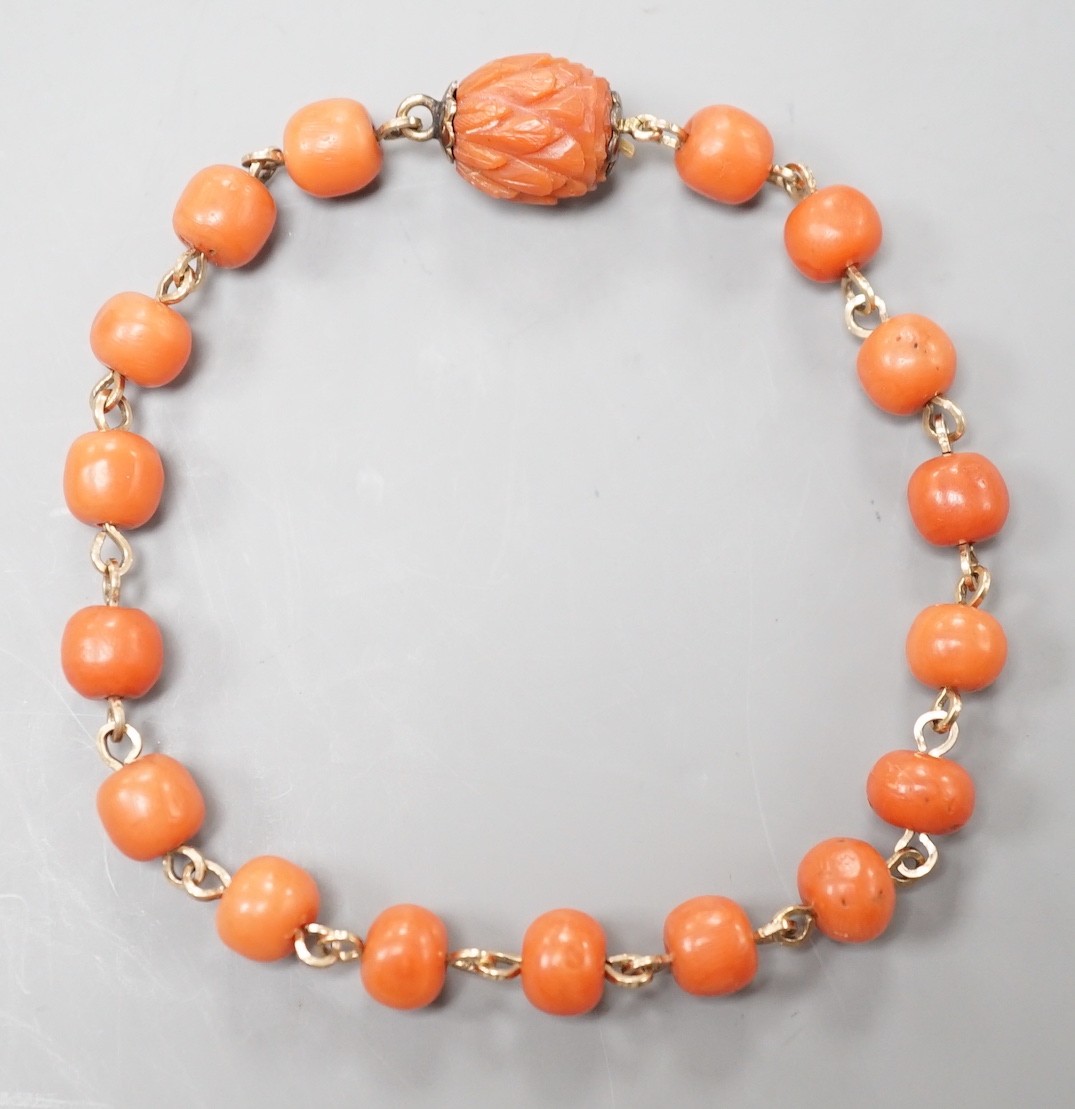 A yellow metal and coral bead bracelet, with carved coral bead clasp, 19.5cm.